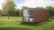 House from a construction transport container sheathed by boards against the background of nature.