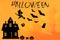 A house cut out of black paper, a witch flying on a broomstick, bats, ghosts, pumpkins and dry tree leaves on a vintage orange bac
