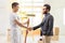House decorator with a roller painter shaking hands with a bearded man in a house