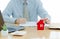 A House on desk envelope with man signing purchase documents in background. while hand complete the insurance policy, rental