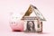 House of dollars and piggy bank on a pink background. The concept of accumulating money for housing