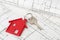 House door key with red house key chain pendant on building plan