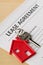 House door key with red house key chain pendant and lease agreement form on wooden desk