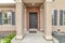 House entrance with portico leading to front door against red brick wall