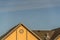 House exterior with roof shingles and round gable window against blue sky