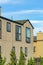 House facade with brown stucco paint and black accent windows and dark roof with blue sky background and backyard trees