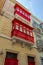 House facade with traditional Maltese wooden balconies painted in red in Cospicua, Malta