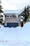 House with gray garage door against snowy driveway yard and roof in winter