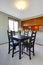 House interior. Simple black dining table set in small dining room with view of the kitchen.