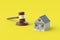 House and judge gavel on yellow background