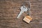 House key on a house shaped keychain resting on wooden floorboards concept for real estate renting property. House model and key