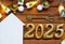 House key with tiny figure of home mock up on festive brown wooden background, lights of garlands. New Year 2025 wooden letters,