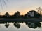 House by the lake. Reflection of a house in the water. Mansion by the river at sunset. The cottage is near the reservoir. Kiev