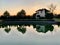 House by the lake. Reflection of a house in the water. Mansion by the river at sunset. The cottage is near the reservoir. Kiev