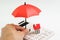 House maintenance and protection and home care service or cost calculation concept, human hand holding small umbrella over group