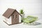 House model, calculator and banknotes on white table. Mortgage concept