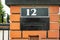 House number 12 above letterbox in red fence