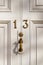 House number 13 on a white wooden front door with bronze handle and elegantly carved lines