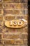 House number 130 carved in wood on a wooden plaque on a brick wall