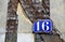 House number 16 on antique rustic wall, old, rusty enamel sign