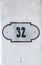 House number 32 thirty two. Black lettering on a white metal plate with brown edge