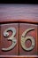 House number 36 on a curved carved varnished door