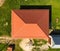 House with an orange roof made of metal, top view. Metallic profile painted corrugated on the roof.