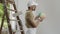 House painter man decorator choose the color using the sample swatch, work the white wall of the house to renovate, a wooden