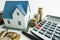 House purchase calculation with small model house, calculator and cash money, investment analysis concept