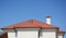 House red clay roof with attic skylight, chimney, roof gutter and copy space.