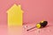 House renovation concept. Home repair and redecorated. Screws and yellow house shaped figure on pink background