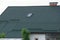 House roof with green tiles and one gray window