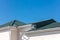 House roof with new gutter system and downspouts on blue sky background