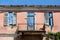 House ruins front wall with cracked destroyed facade and balcony with clear blue sky in background also seen through doors and