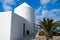 House by sea in Mykonos, Greece. Whitewashed building and palm on sunny blue sky. Typical house architecture and design