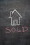 House with sold word on black chalkboard