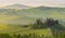 House surrounded by cypress trees among the misty morning sun-drenched hills