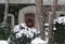 House surrounded by snow-covered evergreen bushes and with wreath on front door