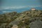 House on top of hilly landscape covered by bushes and rocks