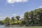 House in the trees beside the lake with flags and bunting flying from deck and dock with boats in the distance - selective focus