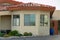 House turret or spire on adobe style home with white stucco exterior and red roof tiles with windows and front yard