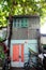 House with wooden window overshadow by big Terminalia catappa tree