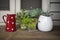 House yard with plants in flowerpots next to a red vintage spotted vase