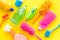 Housecleaning with detergents, soap, cleaners and brush in plastic bottles on yellow background top view mockup