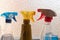 Household cleaning products in spray bottles next to a window -red, blue, yellow, chemicals, clean, copy space