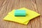 Household concept. Cleaning sponge and yellow micro fiber napkins on wooden background