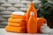 Household freshness Orange liquid washing powder bottle beside neatly folded towels