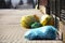 Household rubbish in multicolored sorting bags lies on a city street near the fence of private territory, awaiting export from the