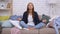 Household and stressless practice. Young calm peaceful woman meditating among scattered garment, sitting on sofa