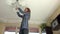 Housekeeper woman climb up and change light bulbs in chandelier.